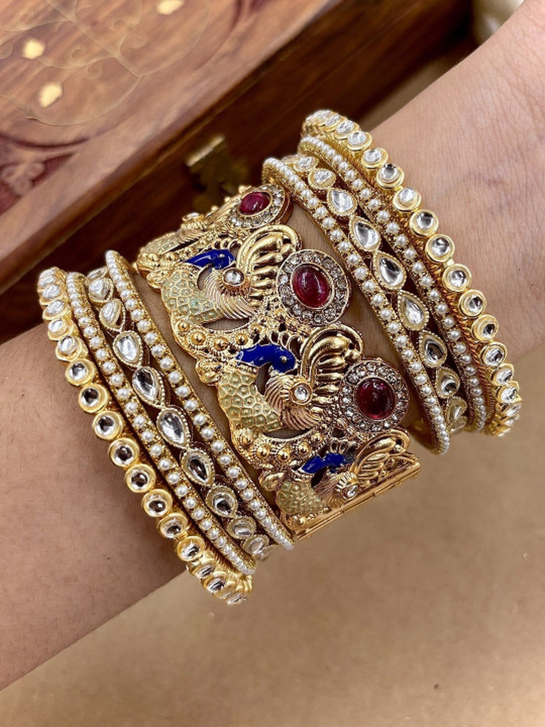 Ishhaara Intricate Gold Peacock Bangle - a gold bangle with peacock design and Kundan Polki stones on a person's wrist